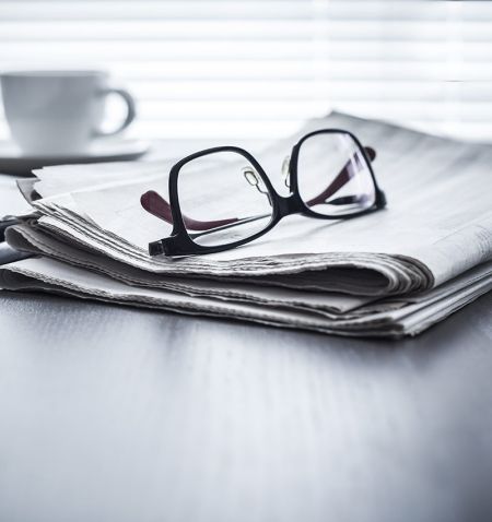 A newspaper with glasses resting on top