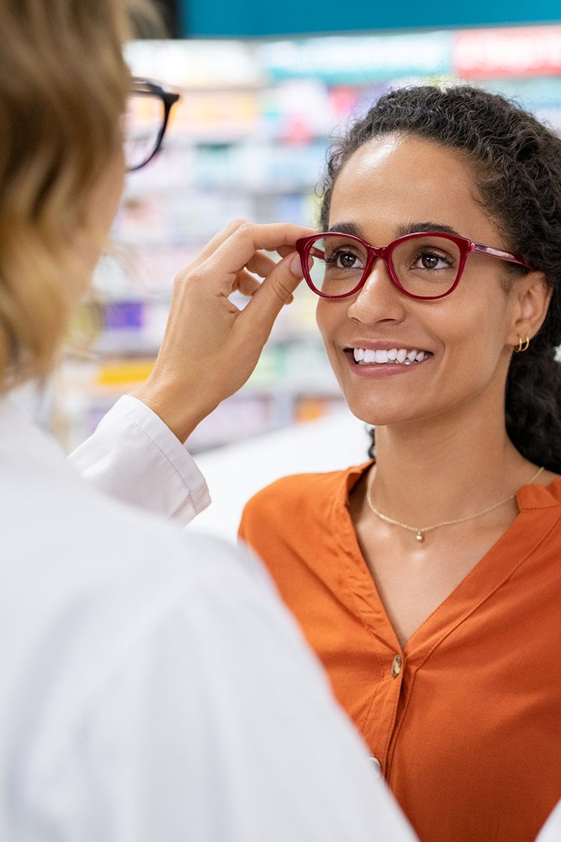 A woman with an orange shirt tries on glasses
