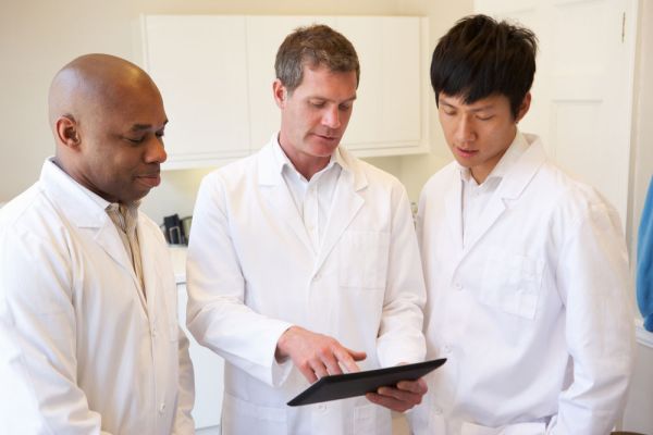 Three doctors having a discussion using digital tablet