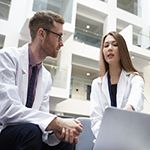 Two doctors discussing a mutual patient in clinical setting